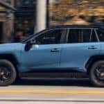 A blue 2022 Toyota RAV4 Hybrid XSE is shown from the side driving on an open road.