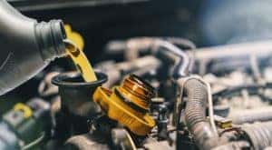 A bottle of oil is shown being poured into an engine.