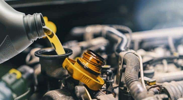 A bottle of oil is shown being poured into an engine.