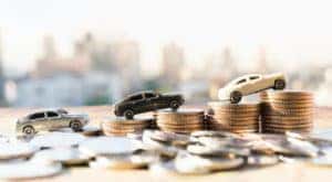 Toy cars are shown places on a stack of coins.