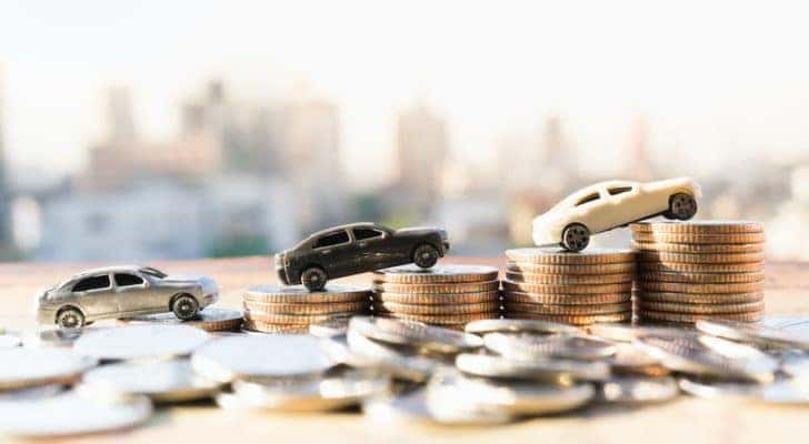 Toy cars are shown places on a stack of coins.
