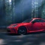 A red 2022 Toyota GR86 is shown driving through a dark forest.
