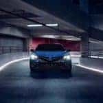 A blue 2023 Toyota Camry SE Hybrid Nightshade Edition is shown driving down a ramp.