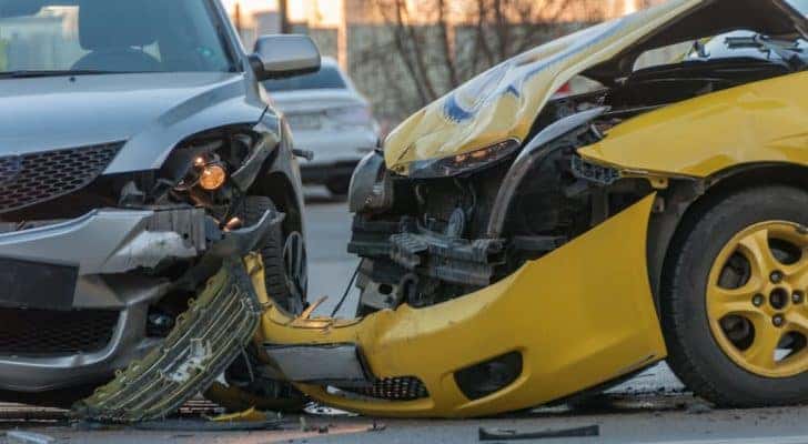 A grey and a yellow car are shown after a collision.