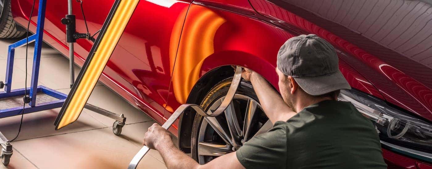 A technician is shown performing paintless dent repair on at a Toyota collision center. 