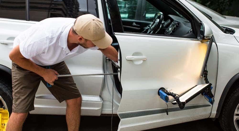A person is shown removing a dent from a vehicle.