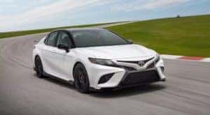 A white 2020 Toyota Camry TRD is shown from the front at an angle after leaving a dealer that has a Toyota Camry for sale.