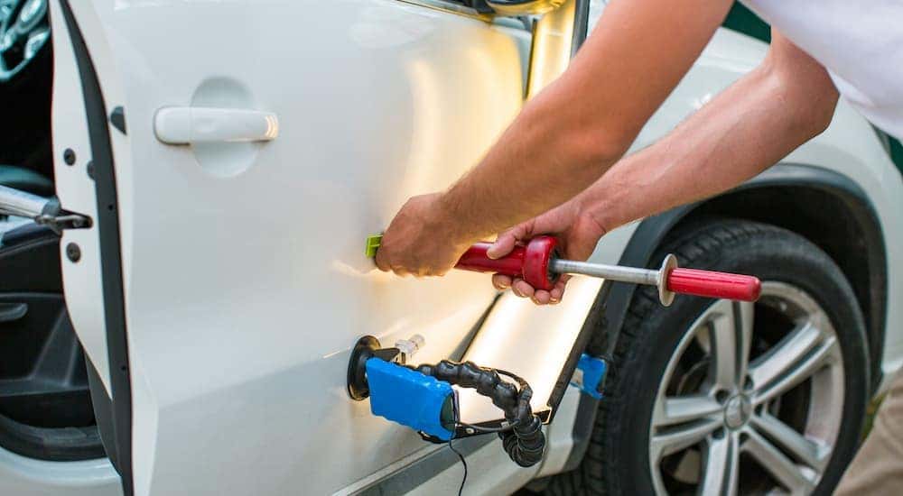 A mechanic is shown fixing a dent.