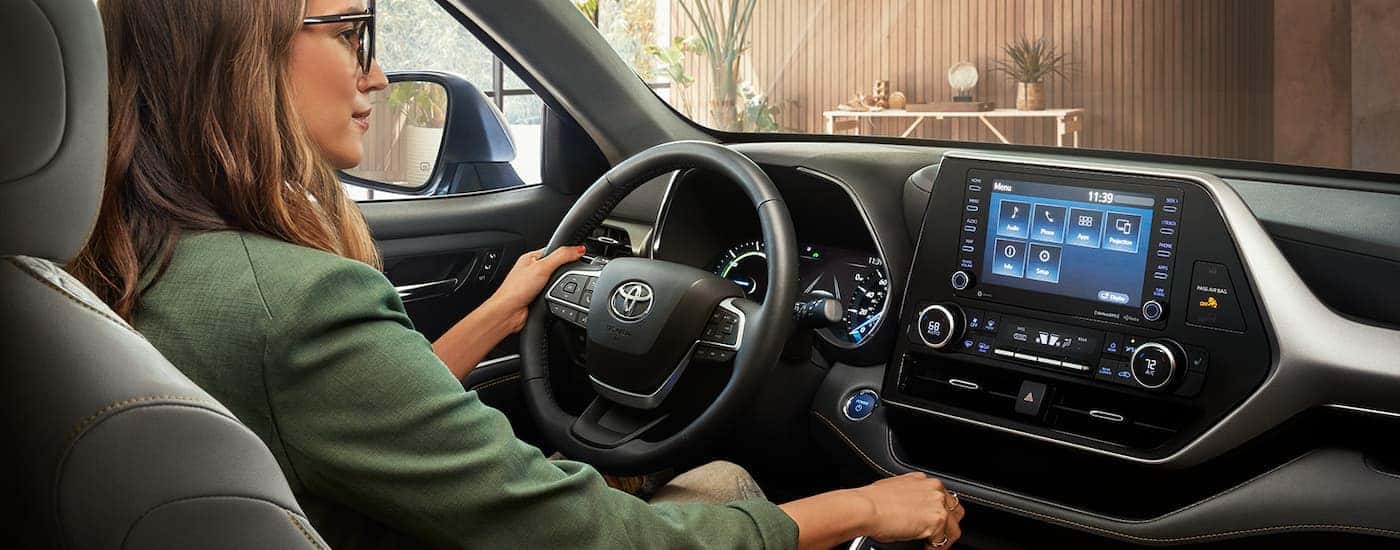 A woman is shown in the drivers seat of a 2022 Toyota Highlander Hybrid.