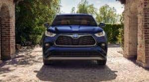 A blue 2023 Toyota Highlander Hybrid is shown from the front parked under a brick arch.