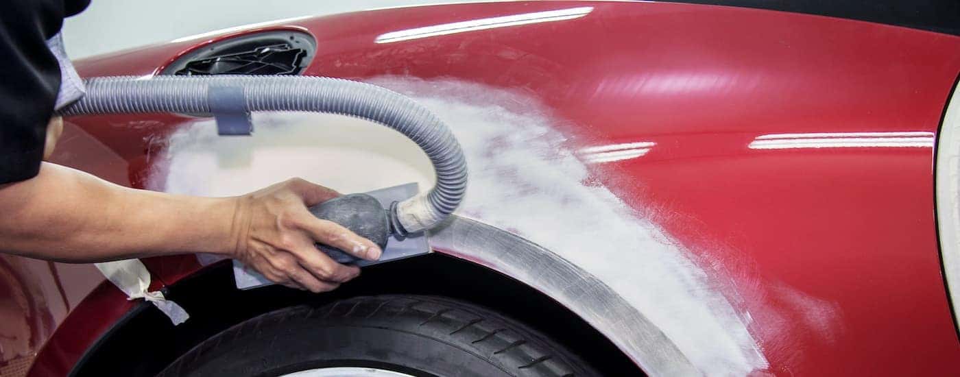 A mechanic is shown smoothing out bodywork.