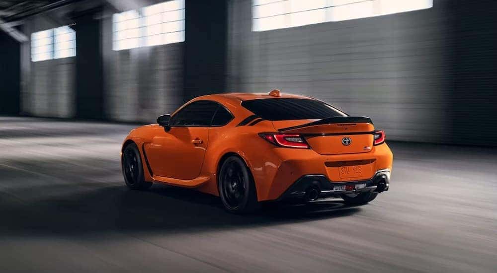 An orange 2023 Toyota GR86 is shown from the rear at an angle after receiving Toyota service in Naperville, IL.