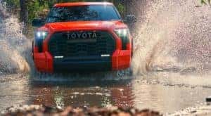 An orange 2022 Toyota Tundra TRD Pro is shown from the front splashing through water.