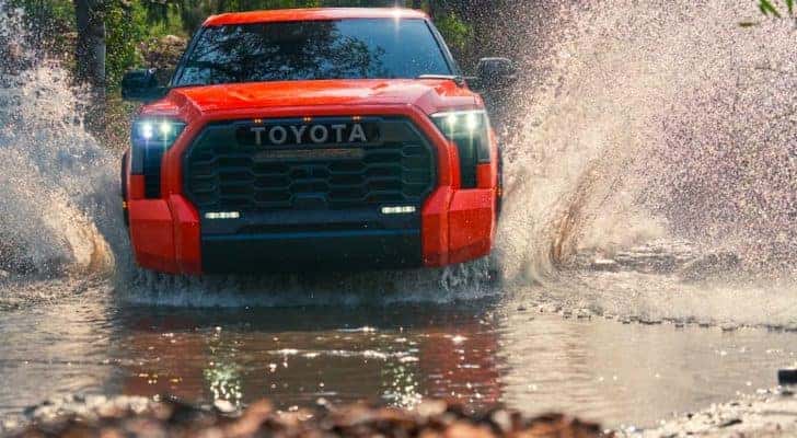 An orange 2022 Toyota Tundra TRD Pro is shown from the front splashing through water.
