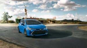 A blue 2022 Toyota Corolla Hatchback is shown driving to a dealer for Toyota service in Naperville, IL.