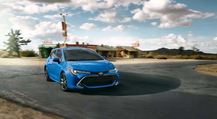 A blue 2022 Toyota Corolla Hatchback is shown driving to a dealer for Toyota service in Naperville, IL.