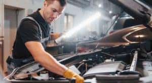 A tech is shown using a light while servicing a car at a service center near you.