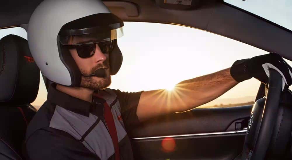 A person in a helmet is shown in a 2023 Toyota Camry TRD. 