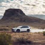 A white 2022 Toyota RAV4 is shown from the side while driving off-road.