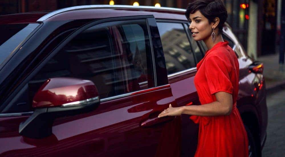A person is shown opening the door of a red 2023 Toyota Highlander Hybrid Platinum.