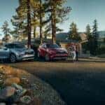 A blue 2023 Toyota Highlander Platinum and a red Hybrid Platinum are shown near a cabin.