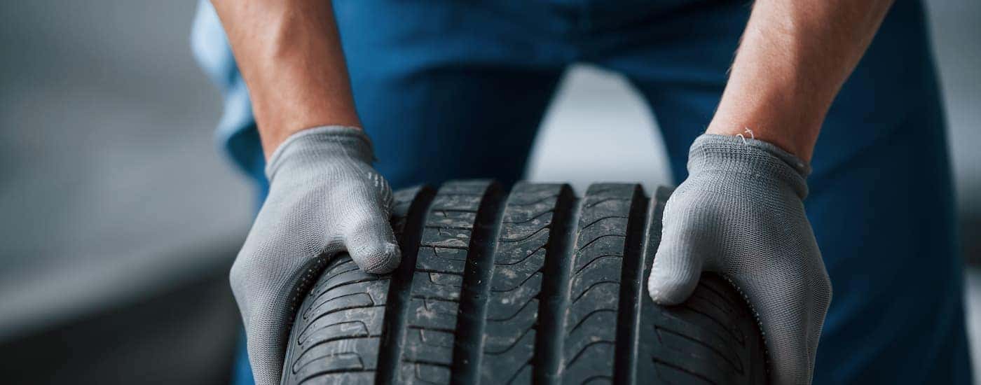 A mechanic is shown holding the a summer tire.