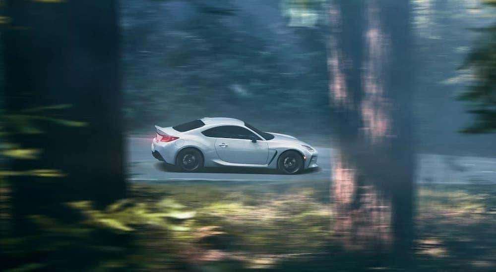A white 2023 Toyota GR86 is shown from the side while driving through the forest after getting Toyota service center near Joliet, IL.