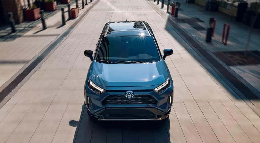A blue 2023 Toyota RAV4 Hybris XSE is shown driving on a road.