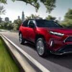 A red 2023 Toyota RAV4 Prime is shown driving on a highway.