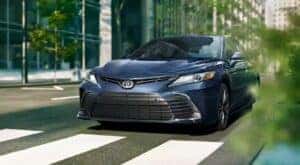 A blue 2023 Toyota Camry for sale near Joliet, IL is shown stopped at a crosswalk.