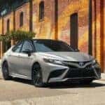 A popular Toyota Camry for sale near Joliet, IL, a silver 2023 Toyota Camry XSE, is shown driving near a building.