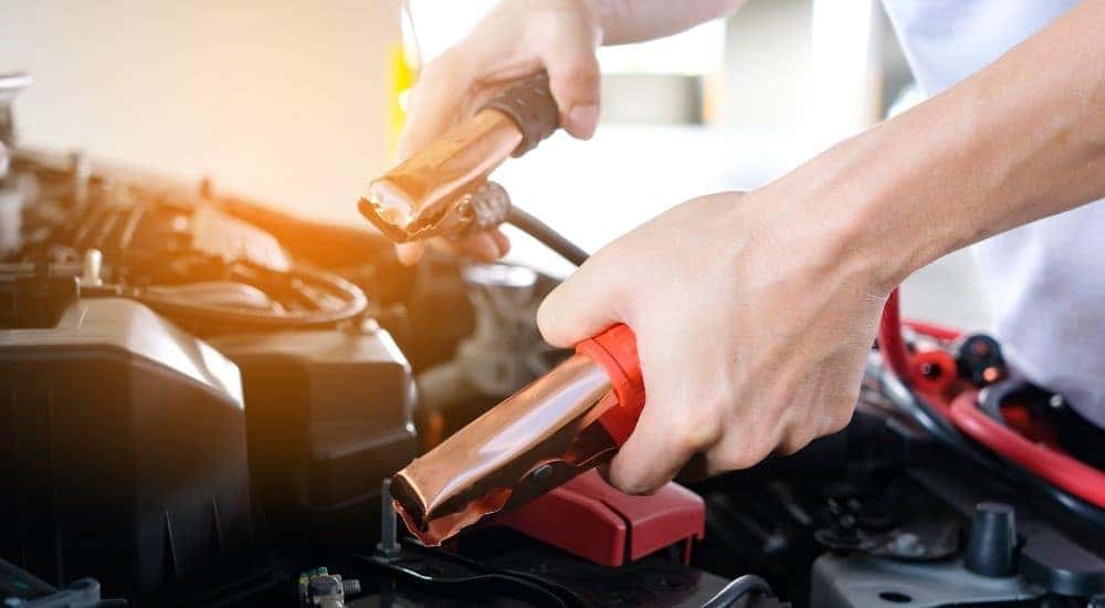 A person is shown using jumper cables before a battery replacement near you.