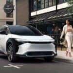 A white and black 2023 Toyota BZ4X is shown parked near a restaurant after having a headlight replacement performed.