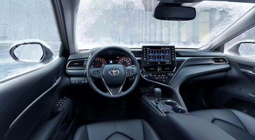 The black interior of a 2023 Toyota Camry is shown from the driver's seat.