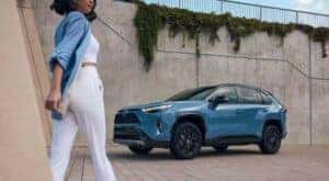 A blue 2023 Toyota RAV4 is shown parked near a concrete wall.