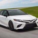 A white 2023 Toyota Camry TRD is shown from the front at an angle on a racetrack.