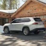 A 2024 Toyota Grand Highlander is shown parked on snow tires near a cabin.