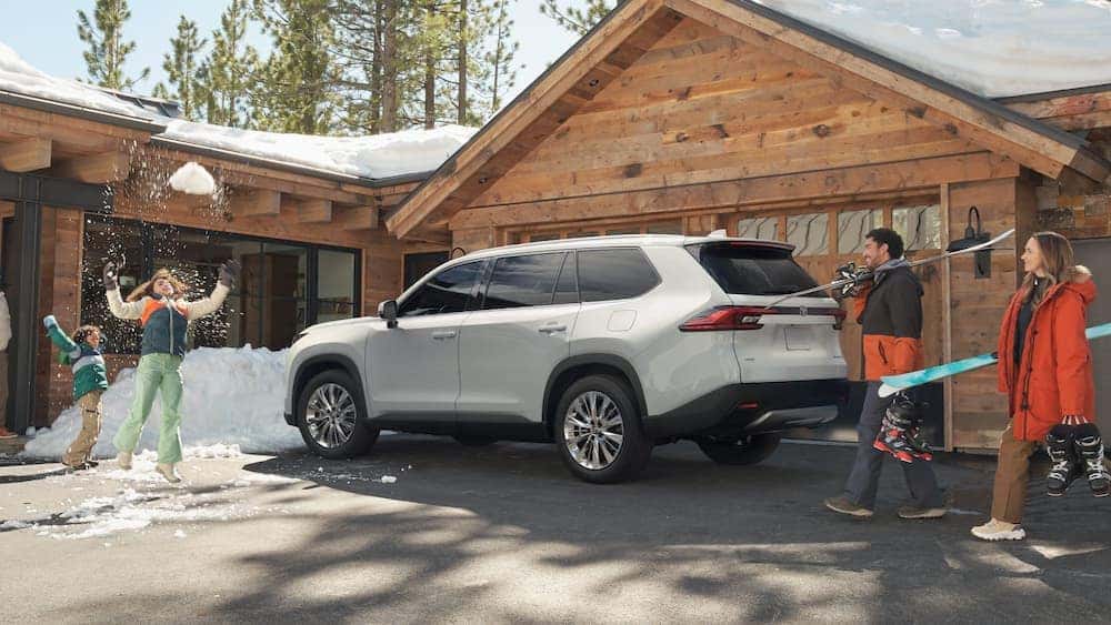 A 2024 Toyota Grand Highlander is shown parked on snow tires near a cabin.