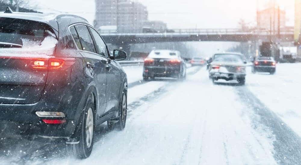 Vehicles are shown driving on a snowy road.