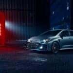 A silver 2024 Toyota GR Corolla is shown parked next to a shipping container at night.