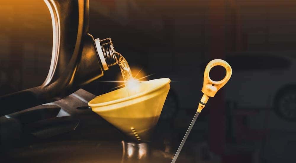 Oil is shown being poured into a yellow funnel during a Toyota oil change.