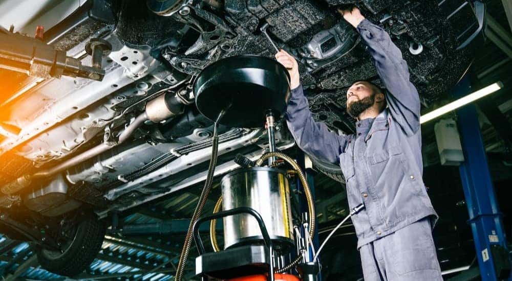 A mechanic is shown performing an oil change on a vehicle.