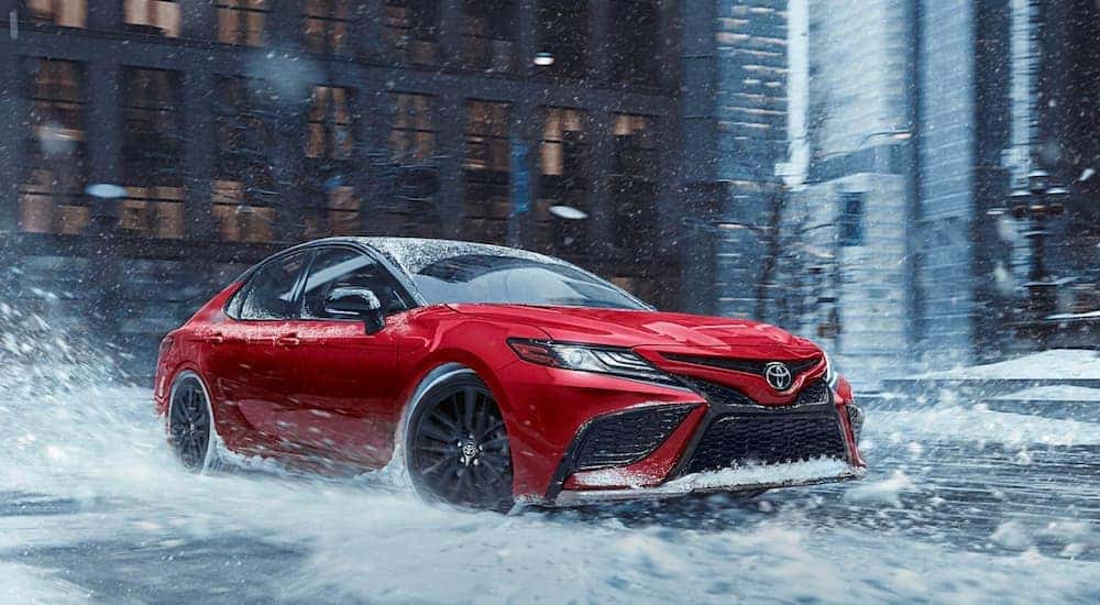 A red 2020 Toyota Camry is shown from the front while driving through snow.