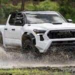 A white 2024 Toyota Tacoma is shown driving off-road.