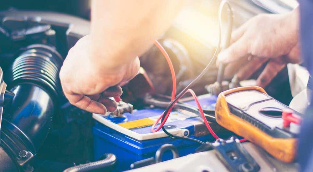 A mechanic is shown testing a battery in a car.