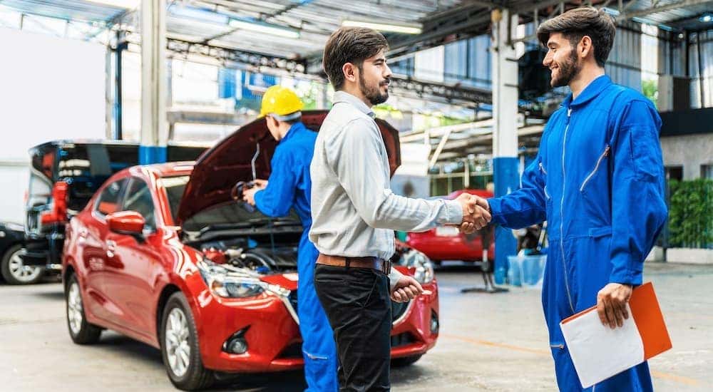 A mechanic is shown shaking hands with a customer at a Toyota service center.