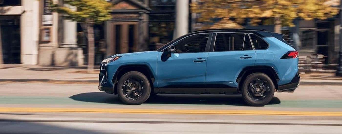 A blue 2024 Toyota RAV4 Hybrid is shown on a city street.