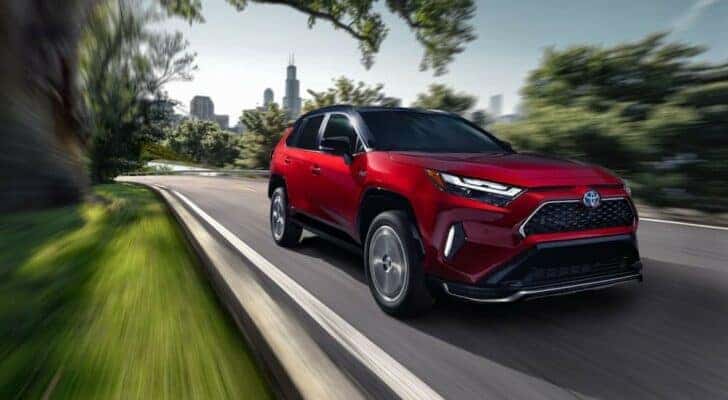 After viewing a Toyota RAV4 for sale near Bolingbrook, a red 2024 Toyota RAV4 Prime, is shown driving on a city street.
