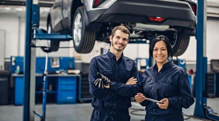 Two mechanics are shown smiling after completing a transmission fluid change.