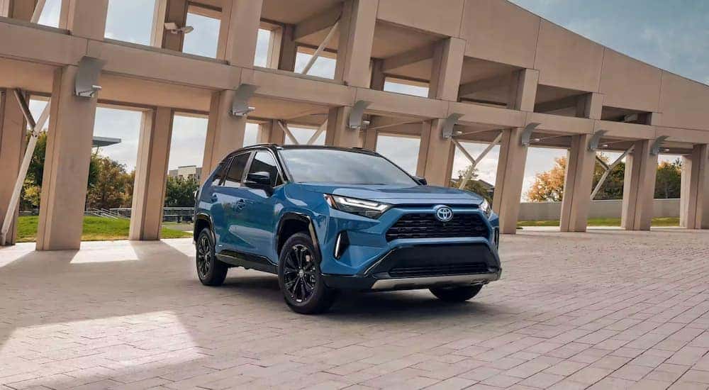 A blue 2024 Toyota RAV4 Hybrid XSE is shown parked near a building.